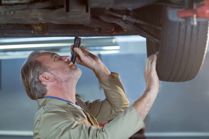 mechanic examining car using flashlight