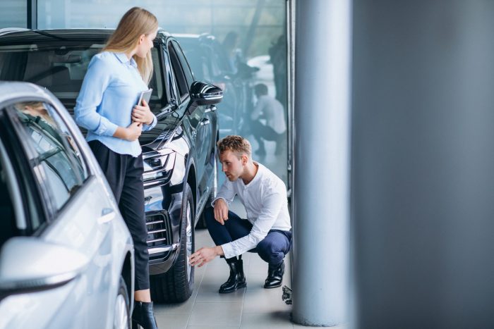 young handsome man choosing car car showroom