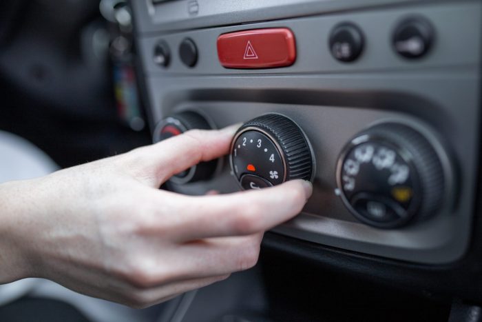 Viaggiare in auto con bambini: 8 consigli per partire senza stress woman hand turning car air conditioning system car air conditioner off button close up view